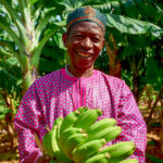 Smiling man holds a large bunch of bananas.