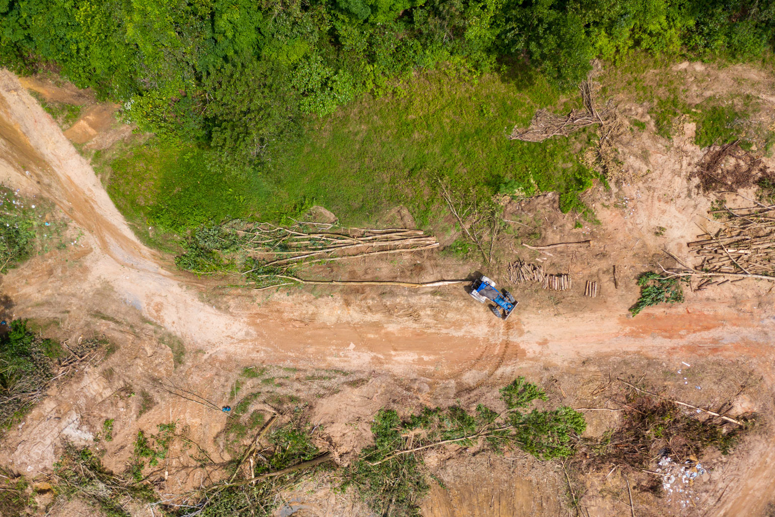 Agriculture, biodiversity loss and climate change - aerial shot of a tractor on a swath of deforested ground.
