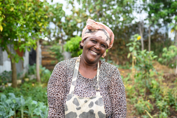 Salome Wairimu standing in her diverse food forest at her homestead. Mbegi, Nakuru County, Kenya 2022.